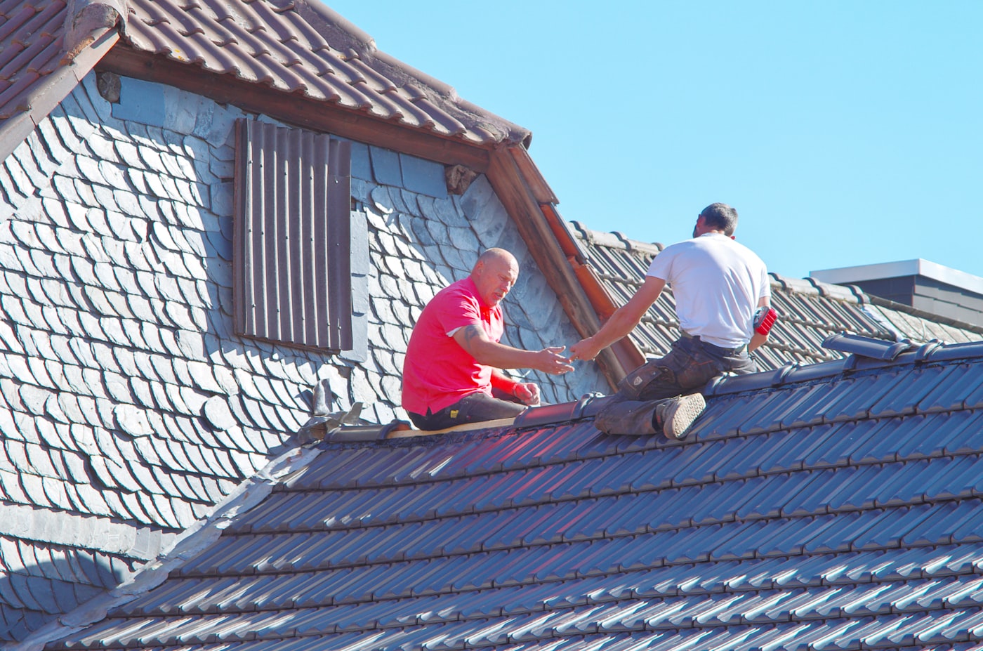 Roofing professionals working on a tile roof